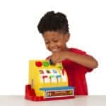 Boy pushing button on Fisher-Price Classics Cash Register.