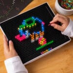 Hand playing with Lite Brite.