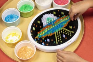 Hand playing with Lite Brite, making a spaceship.