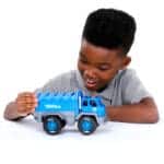 Young boy playing with Tonka Recycling Truck against white background.