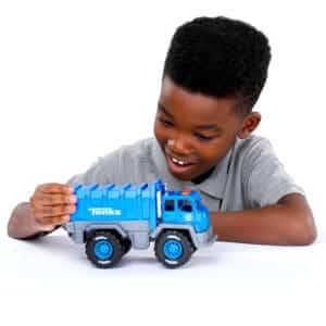 Young boy playing with Tonka Recycling Truck against white background.