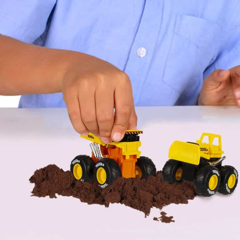 Child's hand playing with two Tonka Monster Metal Movers