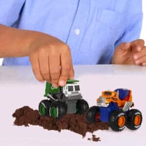 Child's hand playing with two Tonka Monster Metal Movers against white background.