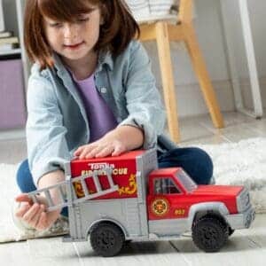 Young girl playing with Tonka Rescue Truck against white background.