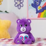 Purple Share Bear on a bed.
