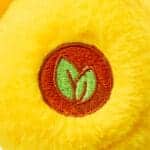 Close-up of a yellow Funshine Bear plush toy from the Care Bears collection, focusing on its embroidered emblem on its foot. The toy features detailed stitching and a soft, textured surface.
