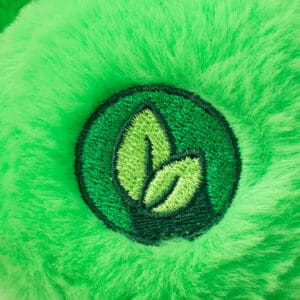 Close-up of a green Good Luck Bear plush toy from the Care Bears collection, showing embroidery on the bottom of bear's foot.