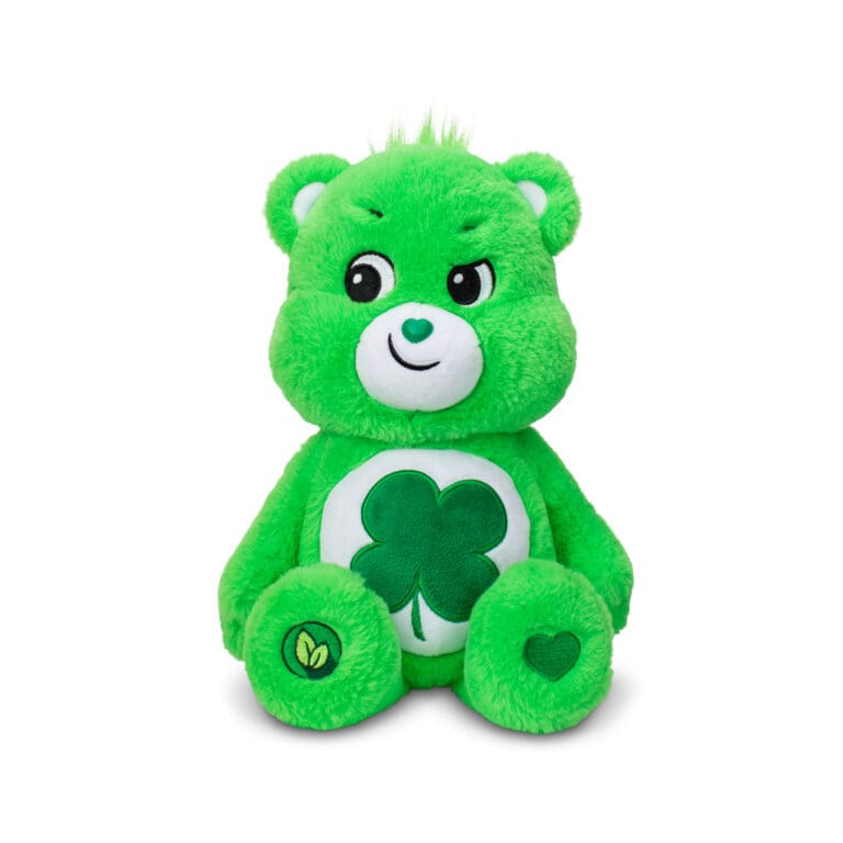 A green Good Luck Bear plush toy from the Care Bears collection is shown against a plain white background. The toy features a four-leaf clover on its belly and a cheerful expression.
