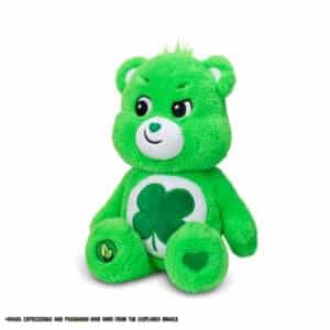 A green Good Luck Bear plush toy from the Care Bears collection is shown against a plain white background. The toy features a four-leaf clover on its belly and a cheerful expression.