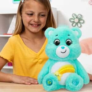 Light Blue Wish Bear on table with young girl smiling.