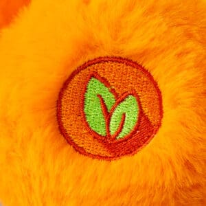 Close-up of an orange Friend Bear plush toy from the Care Bears collection, highlighting its embroidered foot.