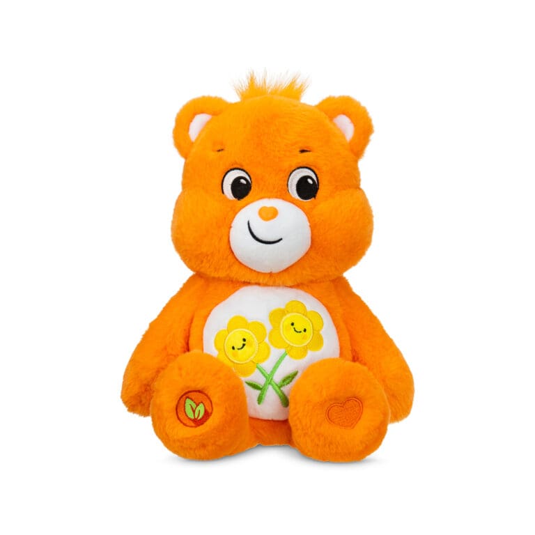 An orange Friend Bear plush toy from the Care Bears collection is shown against a plain white background. The toy features two intertwined smiling flowers on its belly and has a cheerful expression.