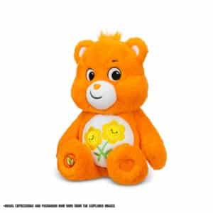 An orange Friend Bear plush toy from the Care Bears collection is shown against a plain white background. The toy features two intertwined smiling flowers on its belly and has a cheerful expression.