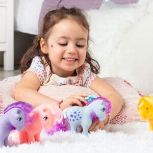 Little Girl smiling and brushing pony's hair