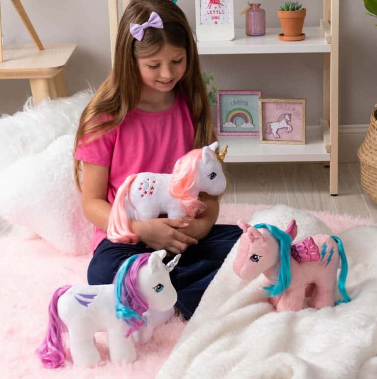 Group shot of girl withplush unicorn and pegasus ponies.