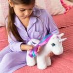 Girl with white plush My Little Pony Unicorn on bed.