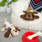 Two Classic Pound Puppies Plush laying down in bedroom.