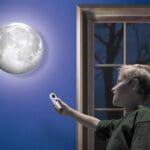 Young boy shining Uncle Milton Moon In My Room against his blue wall.