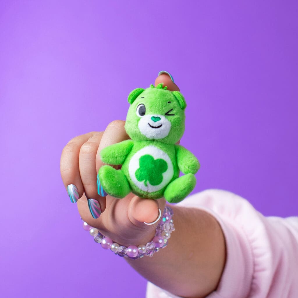 Close up of young girl holding Care Bears Good Luck Micro Plush.