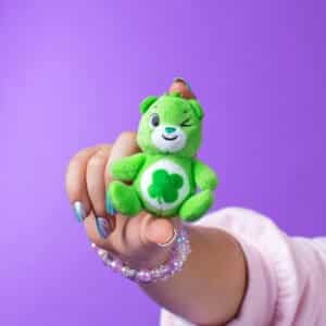 Close up of young girl holding Care Bears Good Luck Micro Plush.