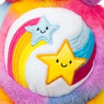 Close-up of a purple Dare to Care Bear plush toy from the Care Bears collection, highlighting its embroidered two intertwined stars on its belly.