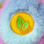 Close-up of a purple Dare to Care Bear plush toy from the Care Bears collection, focusing on its foot, which features detailed stitching of a small star.