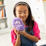 Young girl with purple Curlimals Higgle the Hedgehog.