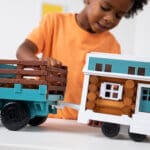 Young boy playing with Lincoln Logs Cruisin' Tonka & Tiny Home.