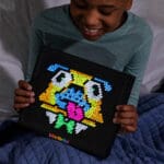 Young boy holding Lite Brite Super Bright that is lit up.