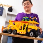Young boy playing with Tonka Steel Classics Classic Car Carrier in bedroom.