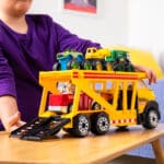 Young boy playing with Tonka Steel Classics Classic Car Carrier in bedroom.