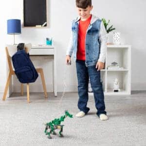 Young boy standing up with Green K'nex K'nexosaurus Rex Motorized Building Toy.