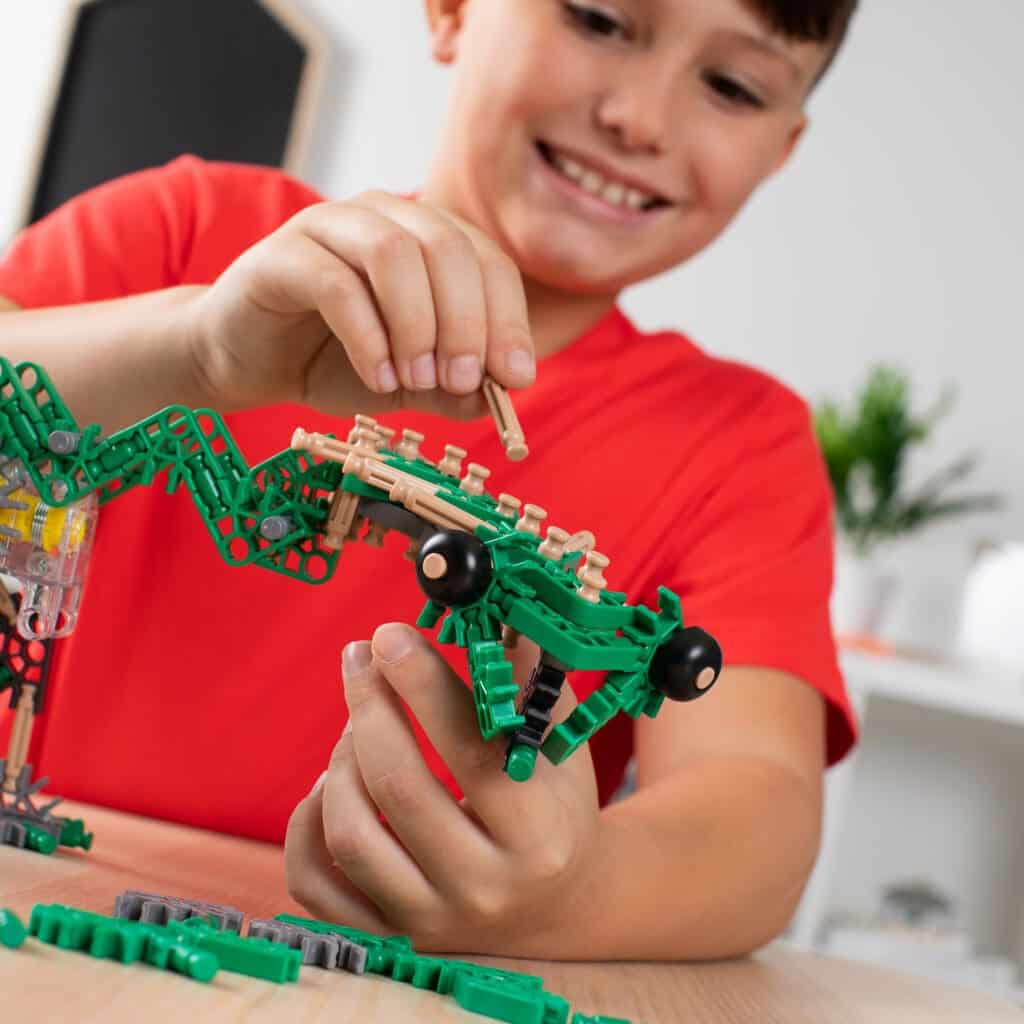 Young boy playing with Green K'nex K'nexosaurus Rex Motorized Building Toy.