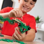 Young boy playing with Green K'nex K'nexosaurus Rex Motorized Building Toy.