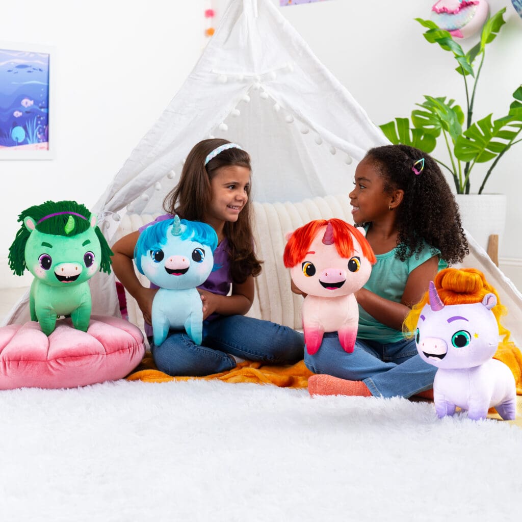 Two young girls playing with four Not Quite Narwhal Plushies in a room.
