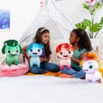 Two young girls playing with four Not Quite Narwhal Plushies in a room.