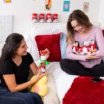 Two young girls holding and playing with Coca-Cola Pop Cans.