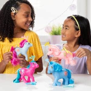 Young girls playing with MLP Celestial Ponies Assortment smiling at each other.