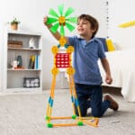 Young boy smiling and playing with Tinkertoy Thirty Model Super Building Set.