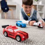 Young boy playing with Tonka Carrier Three Pack Sports Cars on floor.