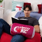 Young boy reading with Coca-Cola Cherry Coke Novelty Plush Can on lap.