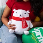 Young girl in room holding Coca-Cola Trendy Polar Bear.