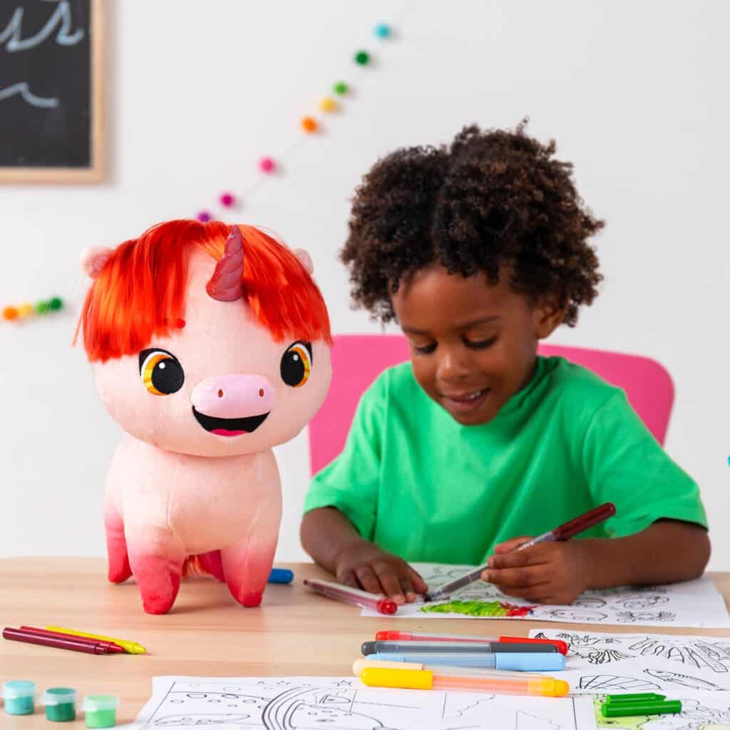 Young boy coloring next to Not Quite Narwhal Pixie.
