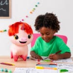 Young boy coloring next to Not Quite Narwhal Pixie.