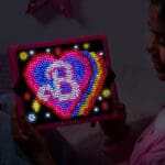 Lite Brite Super Brite HD Barbbie Edition lit up and held by a young girl.