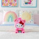 Plush Hello Kitty dressed as Cheer Bear on bed.