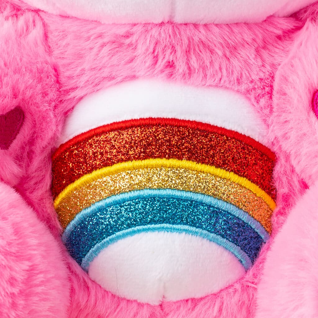 Care Bears Hello Kitty 2 Pack's pink bear's belly is close up, with a pretty glittery rainbow on it.