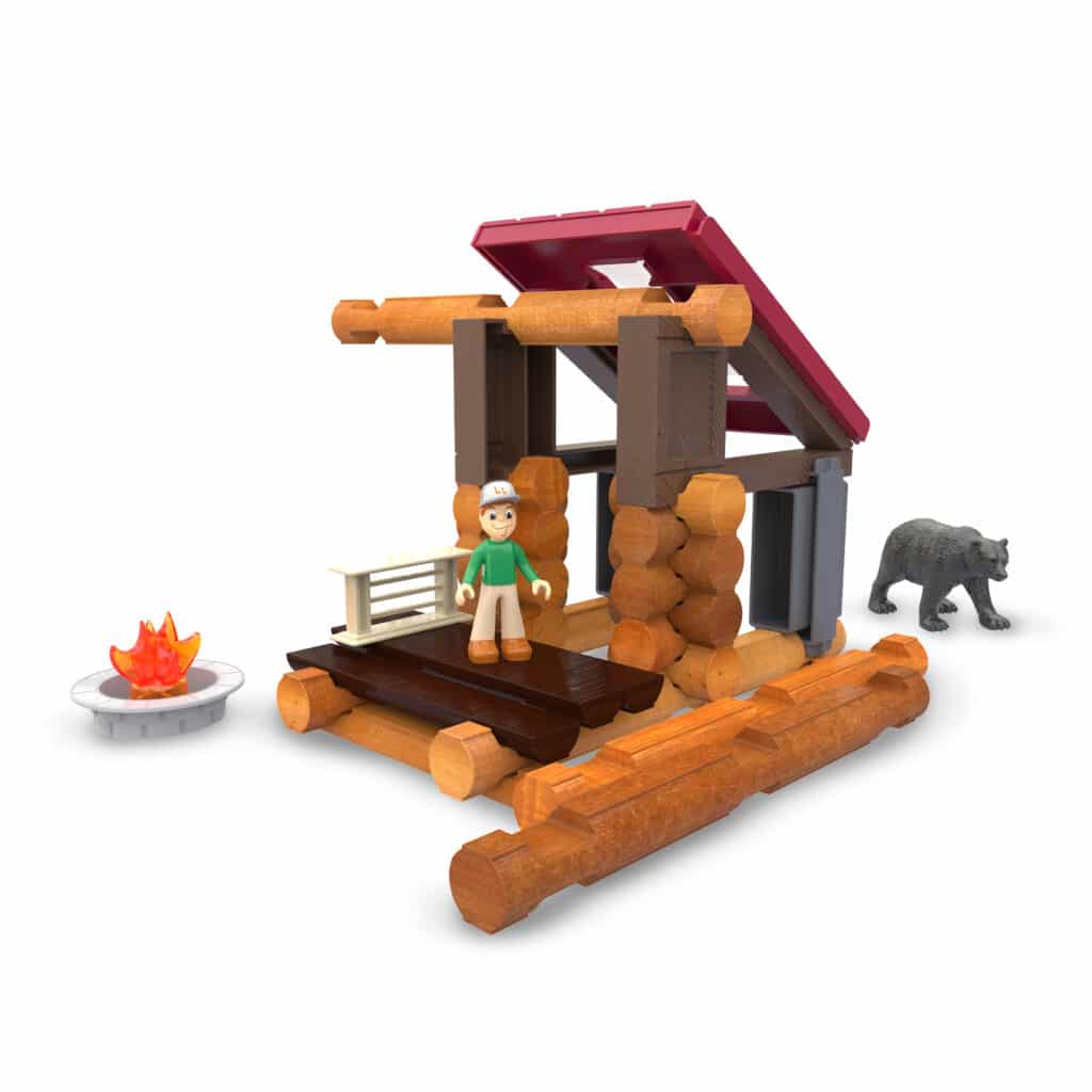 Display photo of the cabin from the back displaying the person, bear and firepit. All included in the Lincoln Logs Adventure Pod Cabin set