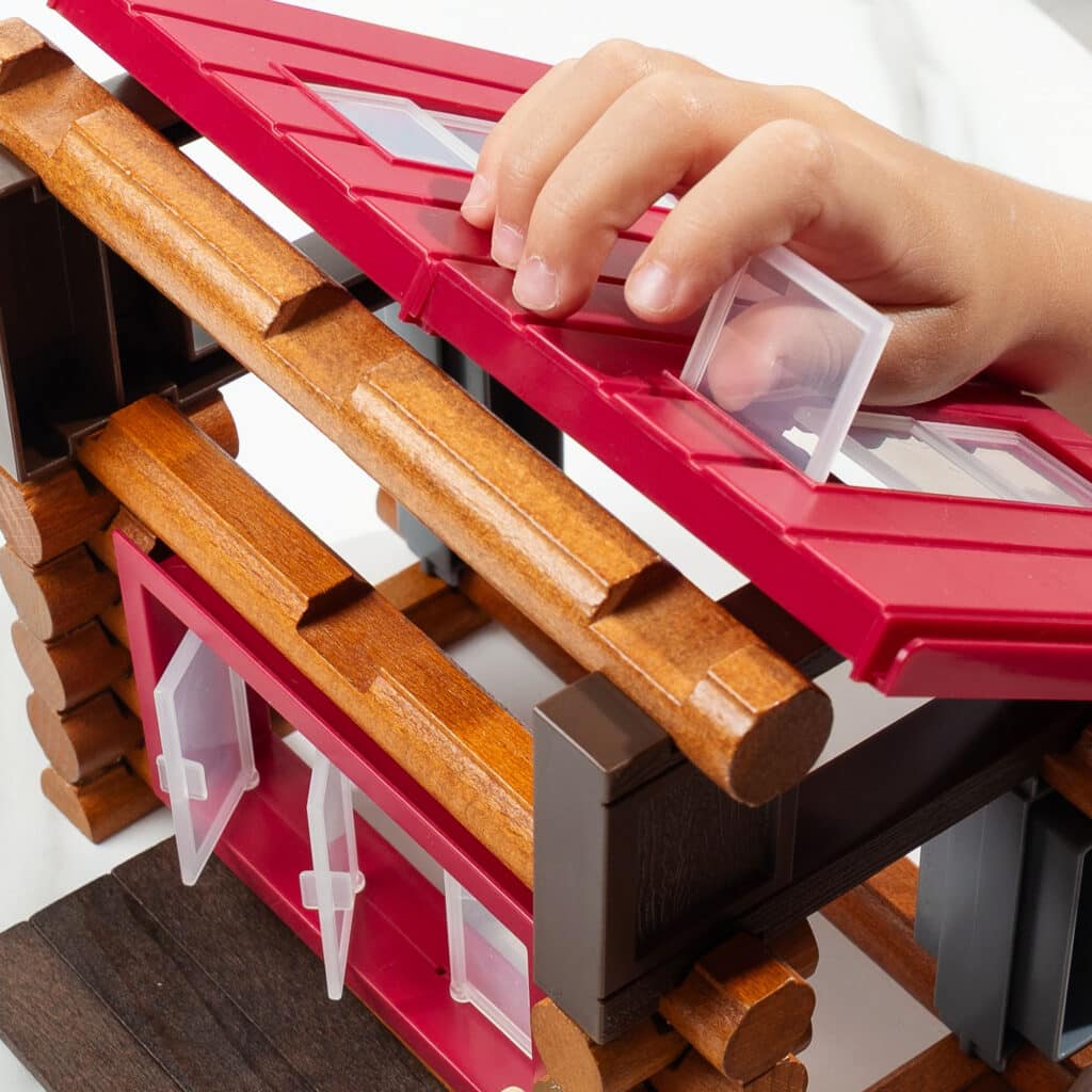 Close up photo of someone attaching the roof onto the base of the cabin from the Lincoln Logs Adventure Pod Cabin