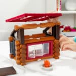 Photo of someone building the roof of the Lincoln Logs Adventure Pod Cabin